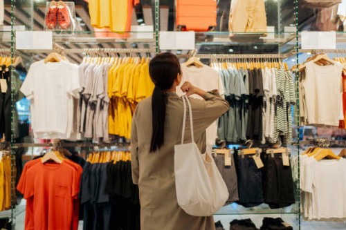 customer contemplating clothing choices in a fashion retail shop - fashion stock pictures, royalty-free photos & images