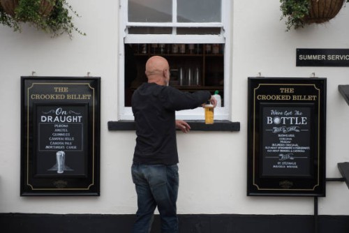 Customer is served a pint of beer via a window at the Crooked Billet pub on July 04, 2020 in Leigh-on-Sea, United Kingdom. The UK Government...