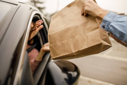 customer receiving coffee and takeaway food order from a service person at the drive through - junk food stock pictures, royalty-free photos & images