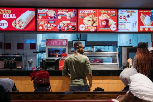 Customers await their orders at the counter of a fast food restaurant in Accra, Ghana, on Monday, April 24, 2023. As many as 48 million people across...