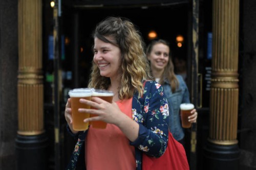 Customers leave with pints of beer for takeaway at The Ten Bells pub in east London on June 27, 2020. The pub serves drinks for takeaway to maintain...