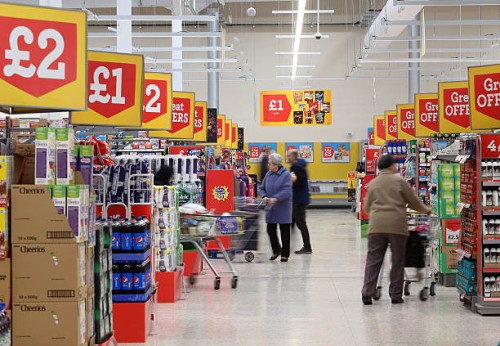 Customers pass along the central aisle inside a Morrisons supermarket, operated by William Morrisons Supermarkets Plc, in Crawley, U.K., on Tuesday,...