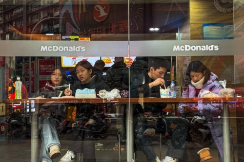 Customers sit at a window-facing table inside a McDonald's restaurant, eating and using their phones on February 12 in Chongqing, China.