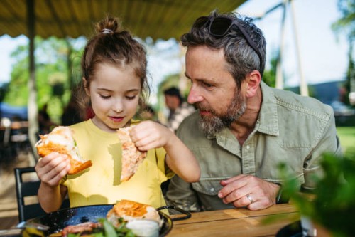 cute girl having dinner with her father. eating hamburger in restaurant, enjoying quality tasty food together. delicious. father's day. - food stock pictures, royalty-free photos & images