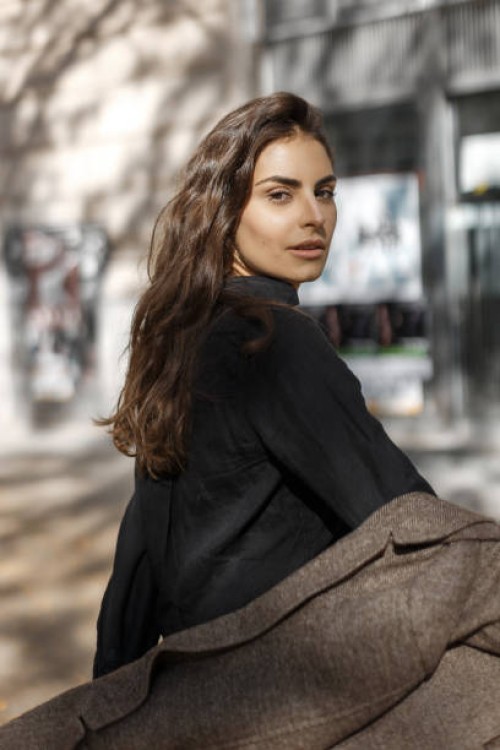cute girl with brown eyes dressed in a brown coat and a black shirt looks curiously at the camera. - fashion stock pictures, royalty-free photos & images