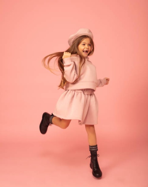 cute little girl jumping in a mini dress against a pink background. - fashion stock pictures, royalty-free photos & images