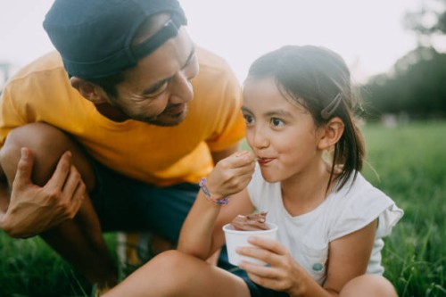 cute young girl enjoying ice cream with her father in park - food stock pictures, royalty-free photos & images