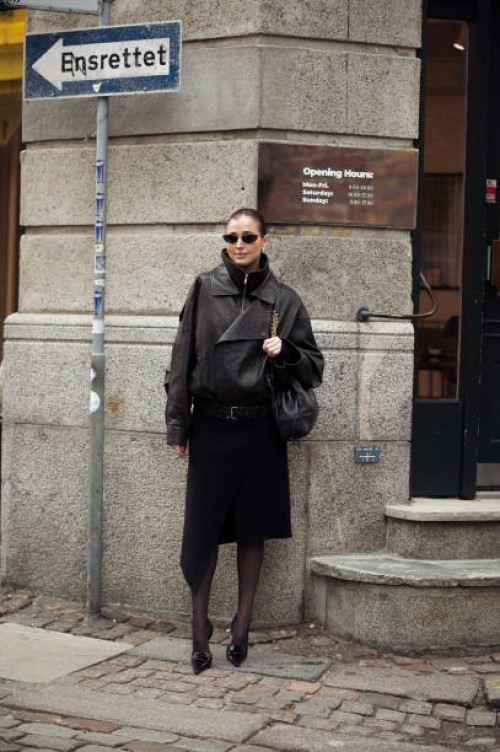 Darja Barannik wears black skirt, dark brown leather jacket, black bag and sunglasses outside the Garment fashion show during the Copenhagen Fashion...