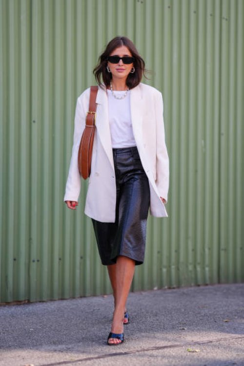 Darja Barannik wears. Black sunglasses, white necklace, white t-shirt, cream oversized blazer jacket, light brown leather bag, shiny black leather...