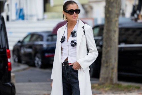 Darja Barannik wears white coat, blouse, sunglasses dark denim jeans, black bag, golden earrings outside Chanel during the Womenswear Spring/Summer...