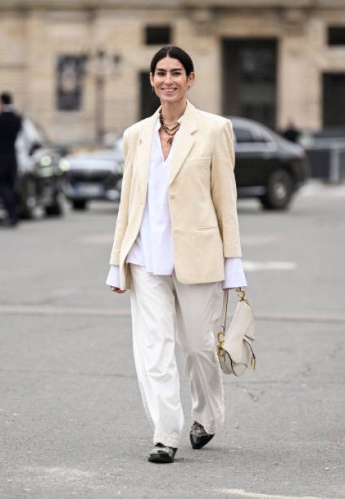 Deborah Reyner Sebag is seen wearing a cream jacket, white button down shirt, white pants, black shoes and black sunglasses outside the Dior show...