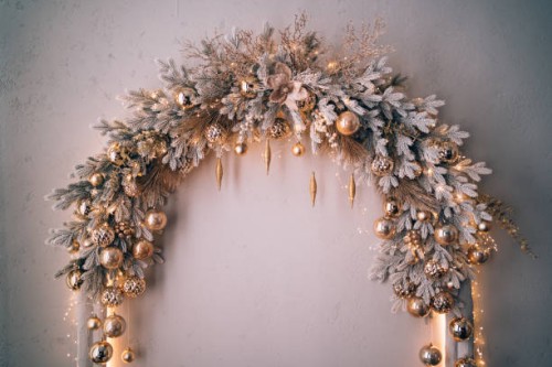 decorated christmas arch with snow-covered fir branches and gold toys: balls and icicles in sparkles. white, silver, grey and golden colors. concept of new year and christmas coming. new year's decorations for photo shoots an
