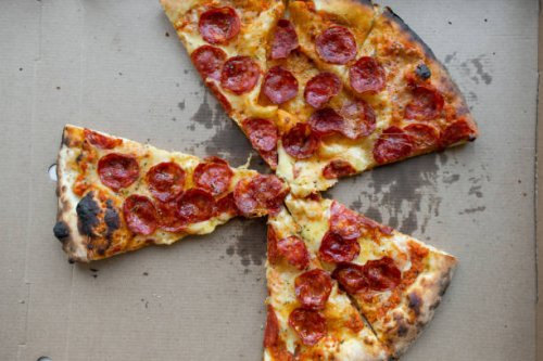 delicious italian pizza in a pizza box and a delivery box, on the table in a pizzeria. sliced pizza slice with tomatoes, pepperoni sausage and cheese. the concept of unhealthy lifestyle, overeating, junk food, fast food. deli