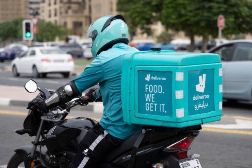 Deliveroo delivery driver on a motorbike waiting in traffic in Dubai, United Arab Emirates on the 26th of October 2023.