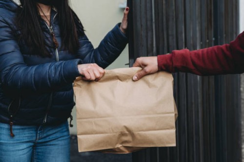 delivery man is delivering a lunch box to a woman - close up view - junk food stock pictures, royalty-free photos & images
