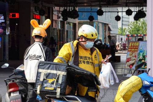 Delivery man wearing a face mask as a preventive measure against the spread of coronavirus holds some takeaway drinks in his hand. The mask mandate...