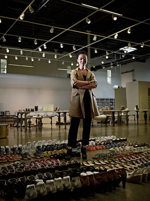 designer standing in showroom surrounded by shoes - fashion stock pictures, royalty-free photos & images