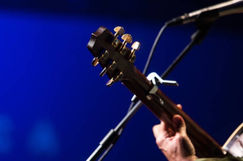 detail of a guitar neck held by a singing guitarist during a concert on a blue background - concert stock pictures, royalty-free photos & images