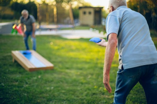 deux vieux amis jouent au trou de maïs dans l’arrière-cour - garden decoration photos et images de collection