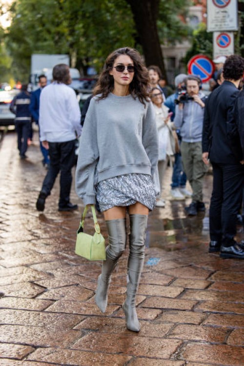 Diletta Bonaiuti wears grey oversized sweater, silver skirt, over knees boots, yellow green bag outside The Attico during the Milan Fashion Week -...