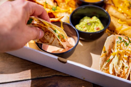 dipping stuffed tortilla in sauce, box with mexican food take out - junk food stock pictures, royalty-free photos & images