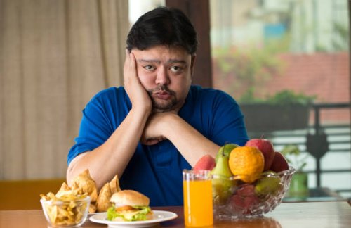 displeased man with unhealthy and healthy food on table - junk food stock pictures, royalty-free photos & images