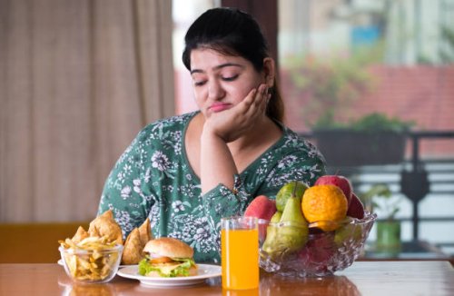 displeased woman with unhealthy and healthy food on table - junk food stock pictures, royalty-free photos & images