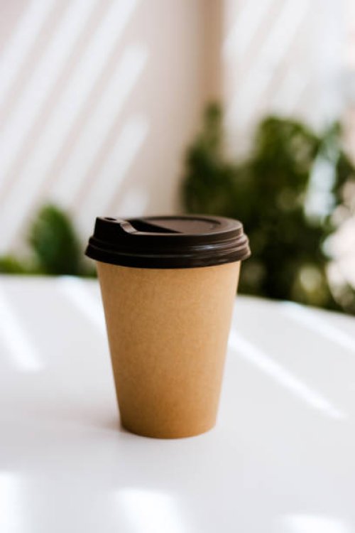 disposable coffee cup on table with plants on background. - junk food stock pictures, royalty-free photos & images