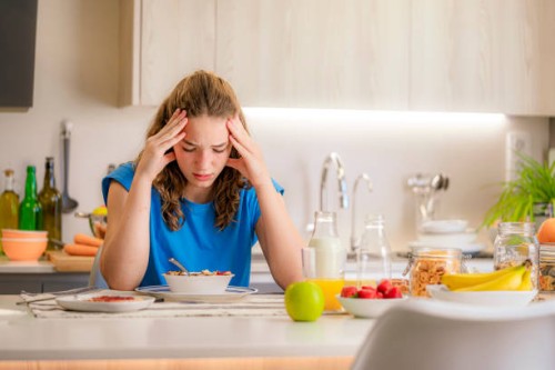 distraught and upset teenage girl sitting at kitchen table. eating disorders. loss of appetite. adolescence problems - junk food stock pictures, royalty-free photos & images