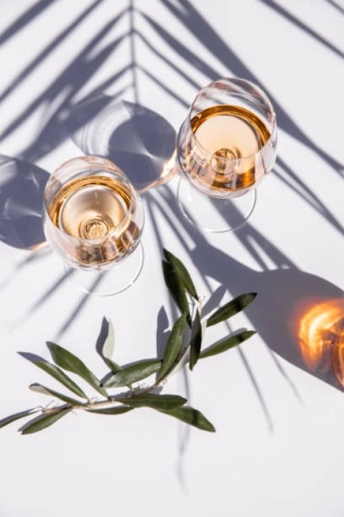 drinking rose wine glasses on white table with olive branch and palm leaf shadow - food stockfoto's en -beelden