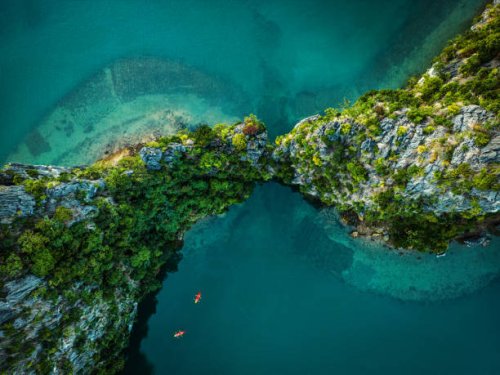 drone view on rocks and canoes floating on turquoise water in the halong bay, vietnam - travel stock pictures, royalty-free photos & images