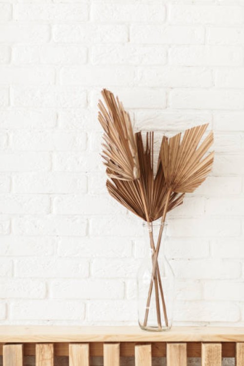 dry gold palm leaf in a glass vase standing on wood shelf. stylish trendy dry flower arrangement on white background. - home decoration stock pictures, royalty-free photos & images