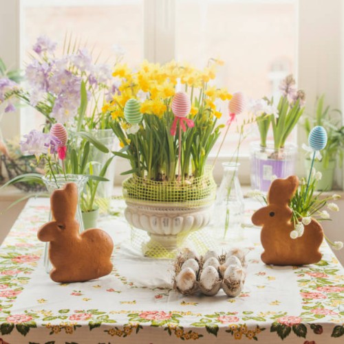 easter table with bunny shaped pastry, easter eggs, daffedils, easter decoration and colorful spring flowers at window background - home decoration stock pictures, royalty-free photos & images