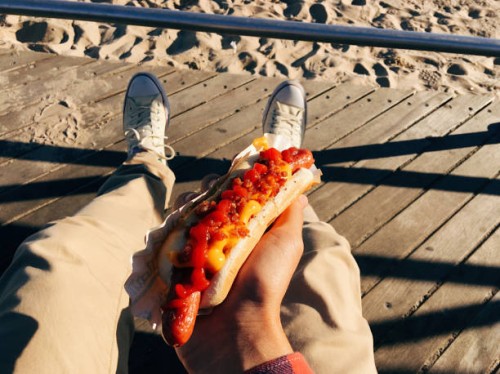 eating famous new york hot dog at coney island boardwalk, personal perspective - junk food stock pictures, royalty-free photos & images