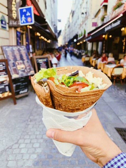 eating french crepe pancake with cheese and fresh vegetables on the street, personal perspective - junk food stock pictures, royalty-free photos & images