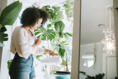 een jonge vrouw wateren haar kamerplanten - home decoration stockfoto's en -beelden