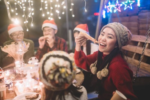 eine asiatische chinesische junge frau holen eine scheibe pizza und blick auf die kamera während der weihnachtsfeier abendessen - garden decoration stock-fotos und bilder