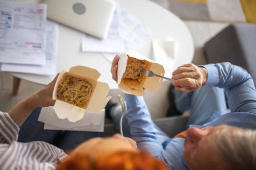elder couple enjoying pasta for lunch at home - junk food stock pictures, royalty-free photos & images