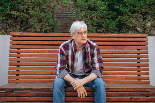 elderly man in glasses with gray hair sitting on a bench - garden decoration photos et images de collection