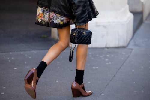 Elle Ferguson wears black leather jacket, Chanel bag, brown shoes, black socksdress with floral graphic print outside Zimmermann during the...