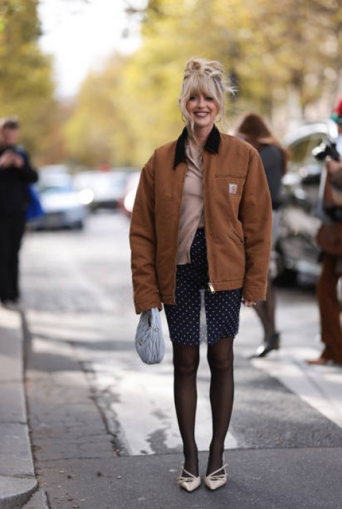 Emili Sindlev is seen wearing a beige cardigan, with a brown jacket from Carhartt, dark blue shorts with white dots, a gray Miu Miu Hobo handbag,...
