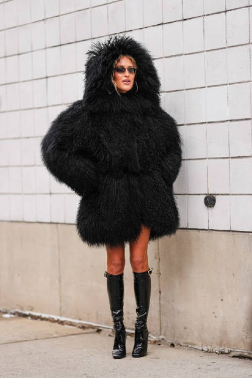 Emili Sindlev wears black faux fur shearling hooded Michael Kors mongolian coat, shiny black knee high heeled boots leather shoes, outside Michael...