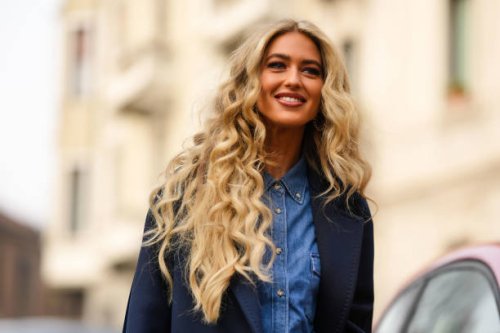 Emili Sindlev wears black leather and gold large earrings from Chanel, a navy blue wool long coat, a blue denim buttoned shirt / cargo pants...
