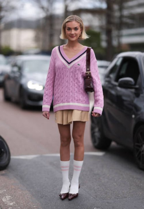 Emilia Silberg is seen wearing a Lacoste pink sweater, Lacoste tan beige skirt and maroon bag outside Lacoste Show during the Womenswear Fall/Winter...
