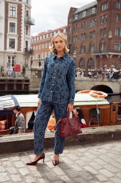 Emilia Silberg wears blue denim pants and matching shirt with flower pattern and burgundy bag attends the VIP guest trip with a boat to the Marimekko...