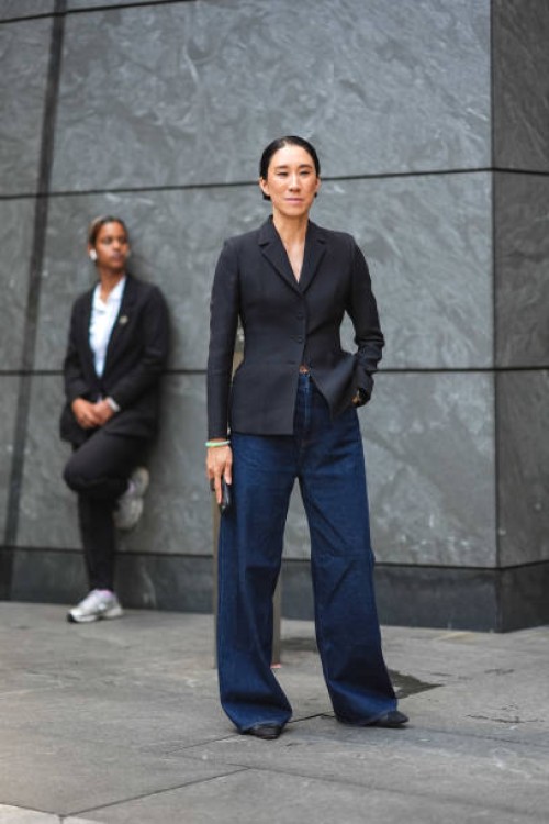 Eva Chen wears a dark gray oversize blazer jacket, blue flared wide-leg denim jeans pants, ballerina shoes, outside Grace Ling, during New York...