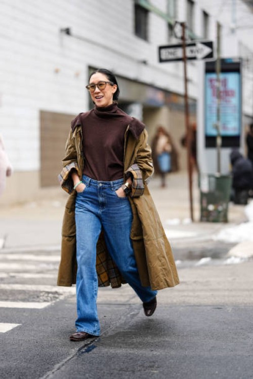 Eva Chen wears dark brown sunglasses, dark brown turtleneck sweater, olive green plaid pattern cuffed trench coat, navy blue midrise washed loose...