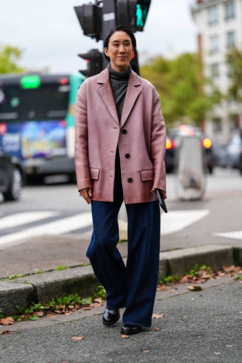 Eva Chen wears dark gray sweater, dark pink oversized blazer jacket, navy blue denim jean pants, shiny black leather boots, outside Chloe, during the...