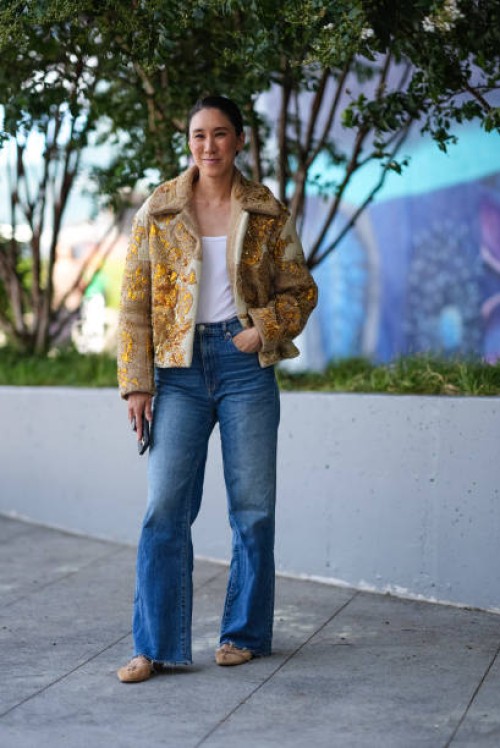 Eva Chen wears white tank top, light brown cream gold pattern detail oversized jacket, washed denim jean pants, light brown ballerina flats leather...