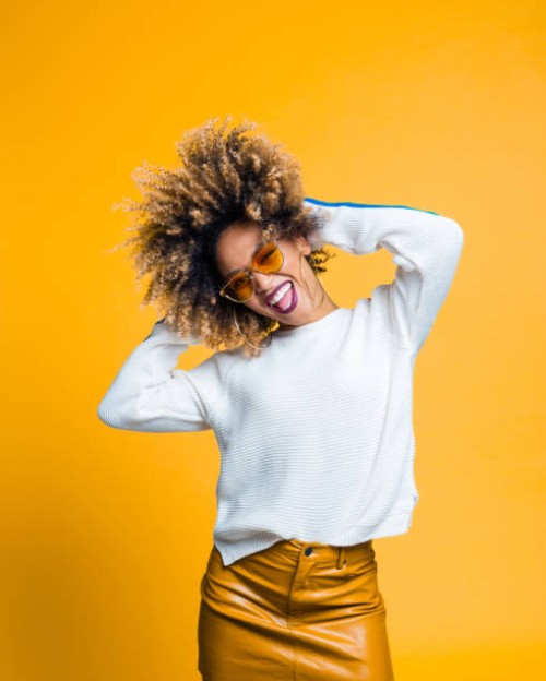 excited afro young woman dancing against yellow background - fashion stock pictures, royalty-free photos & images